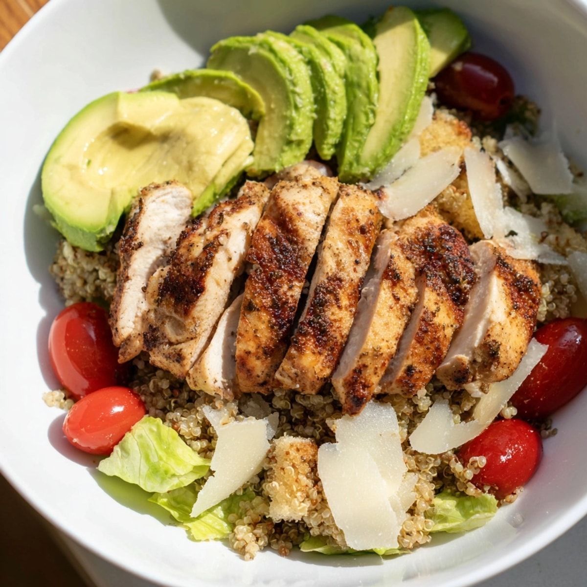Close-up of a vibrant Avocado Chicken Caesar Grain Bowl with grilled chicken slices.
