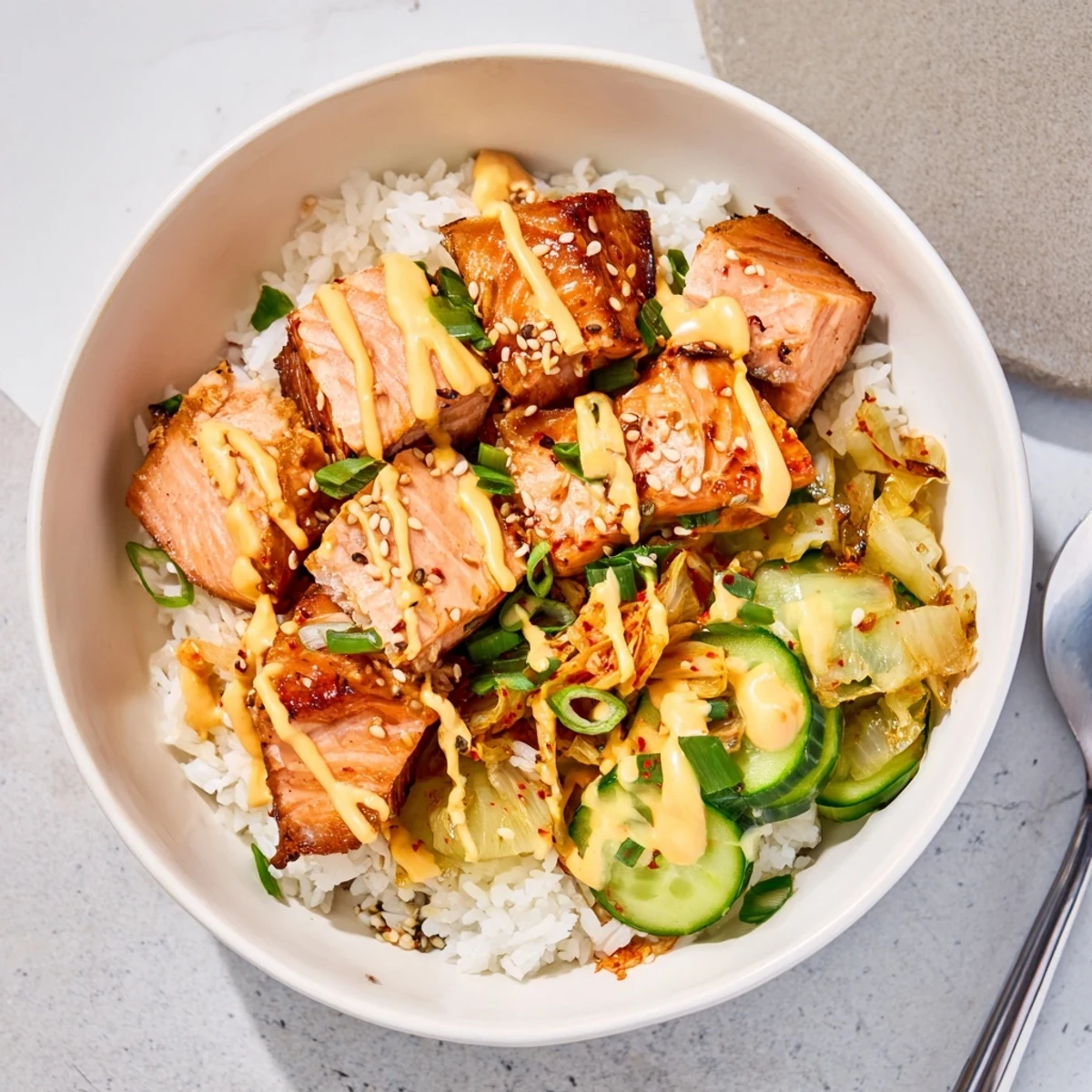 Crispy Salmon Rice Bowl garnished with spicy mayo, kimchi, and fresh avocado slices.