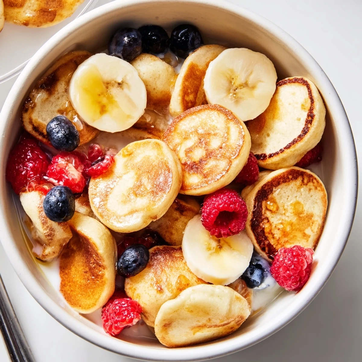 Delicious mini pancake cereal topped with sliced bananas, ideal for a fun morning treat.