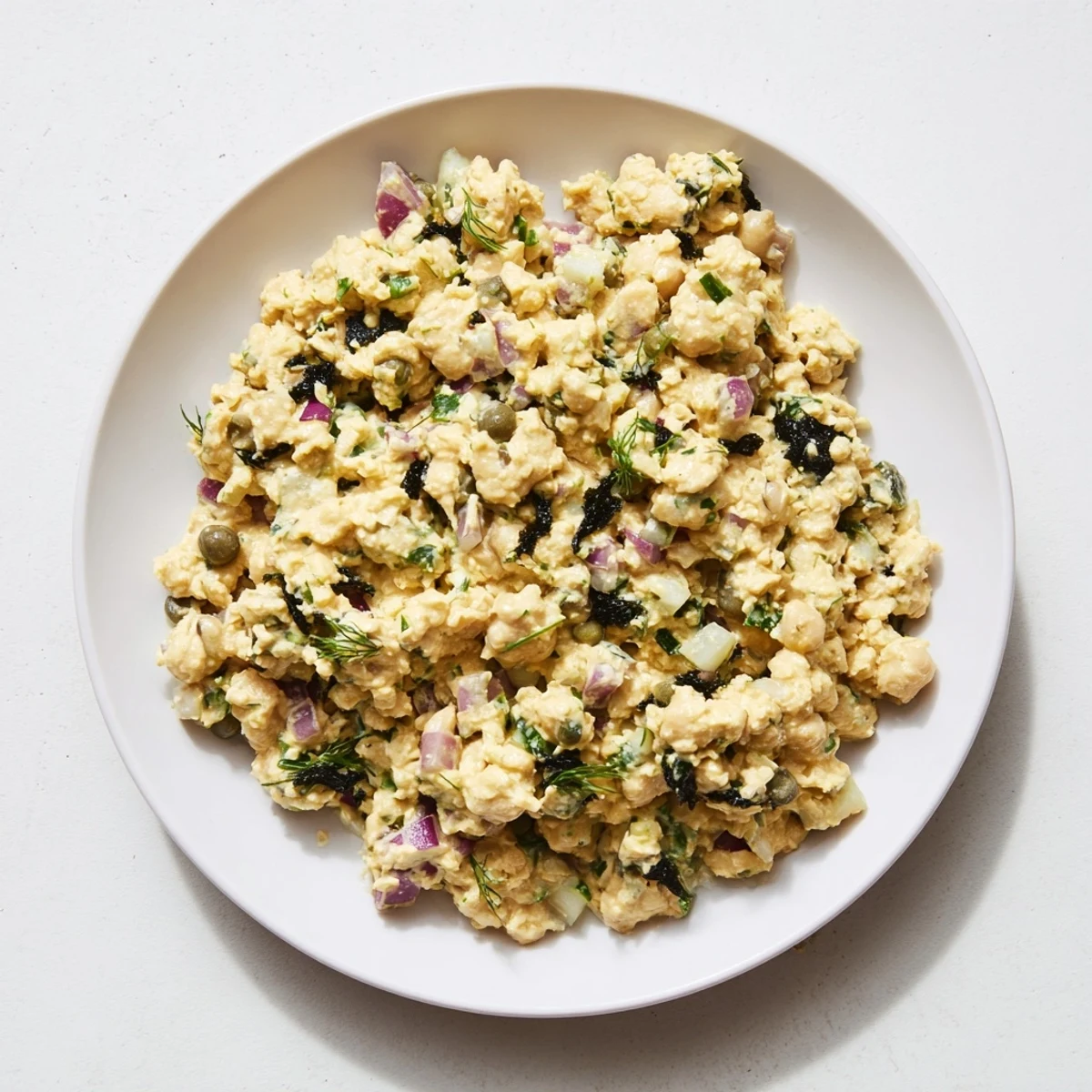 Creamy chickpea tuna salad, the vegan lunch, served alongside whole-grain bread and fresh greens.