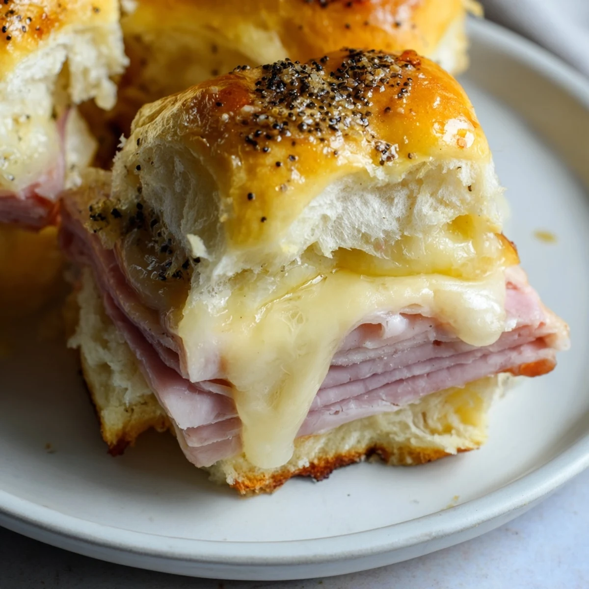Deliciously gooey Baked Ham and Cheese Party Sliders featuring layers of ham and melted Swiss cheese.