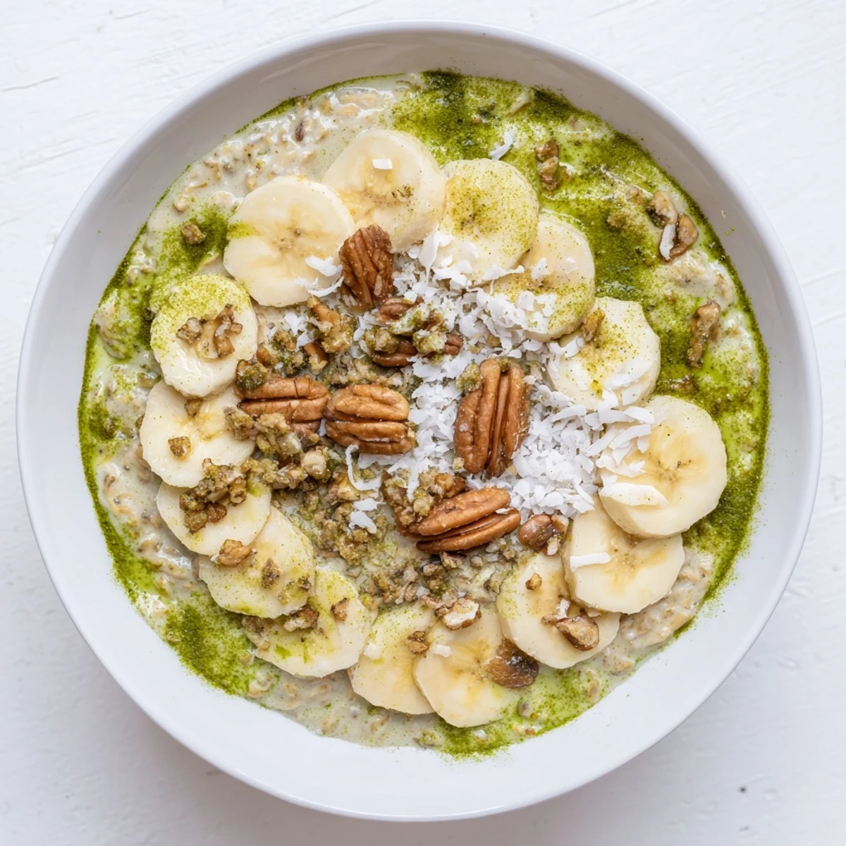 Creamy High-Protein Eggnog Matcha Overnight Oats with banana slices and toasted coconut, ready to eat!