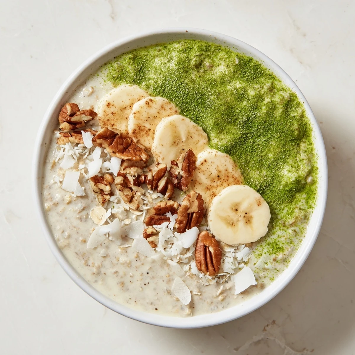 A bowl of refreshing High-Protein Eggnog Matcha Overnight Oats with a sprinkle of warming cinnamon.