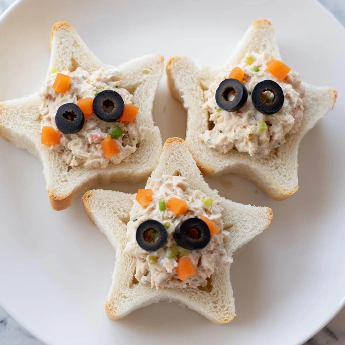 Golden mini starfish sandwiches filled with tuna, garnished with olive eyes, ready to serve and enjoy.