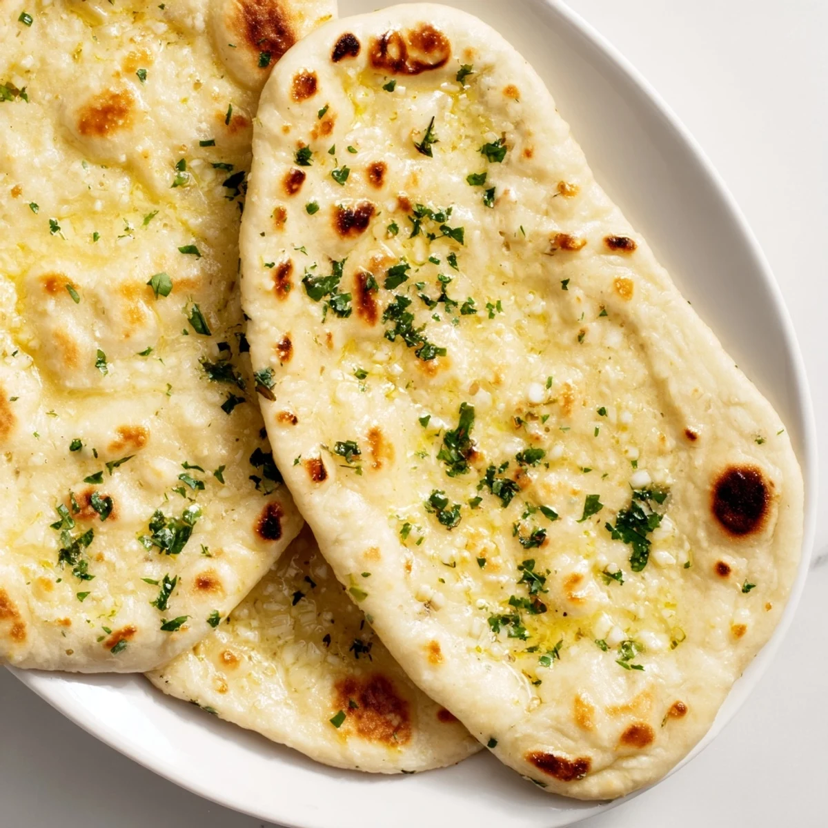 Golden-brown Homemade Garlic Naan Bread, hot off the pan, brushed with fragrant garlic butter.