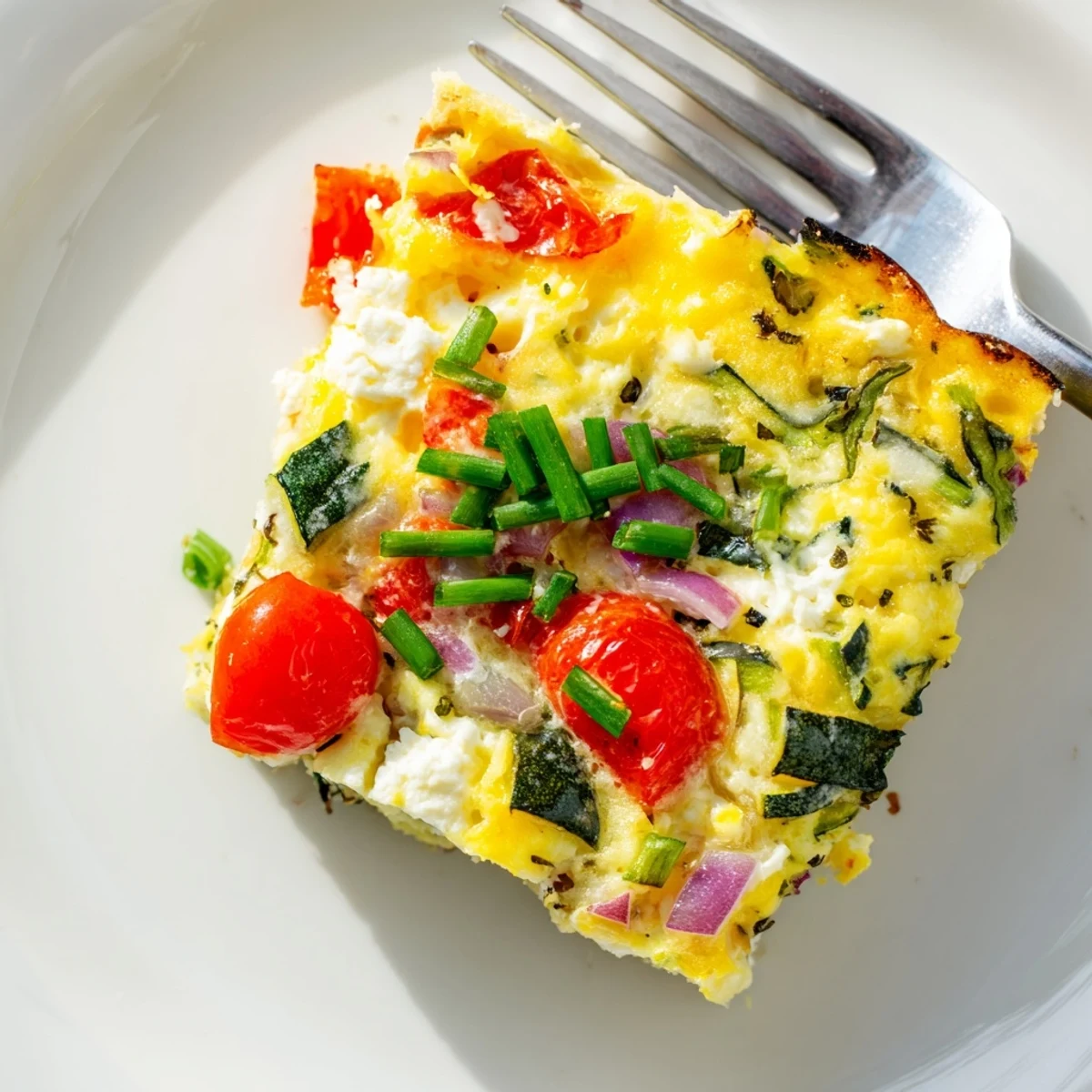Fluffy sheet pan eggs with cottage cheese, dotted with red bell peppers, spinach, and cherry tomatoes on a baking sheet.  