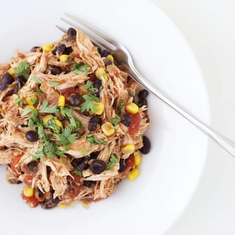 Juicy, shredded Slow Cooker Salsa Chicken, perfect for tacos, boasting vibrant red salsa sauce.