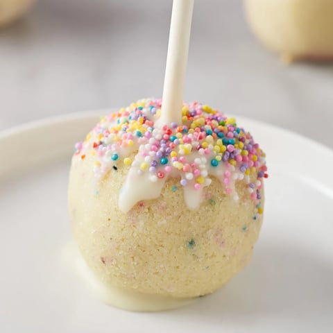 Lightened-Up Sugar Cookie Cake Pops, coated in white chocolate and covered in colorful sprinkles.