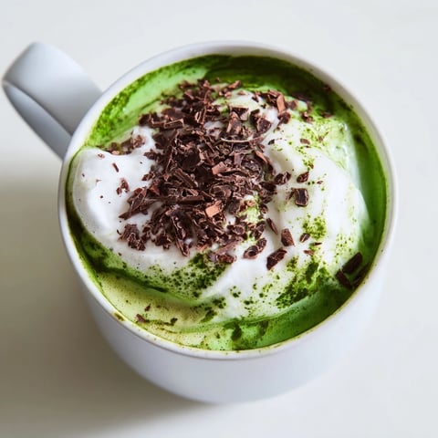 Steaming Collagen Peppermint Mocha Matcha Latte, a vibrant green and cocoa-colored drink, topped with creamy whipped cream.
