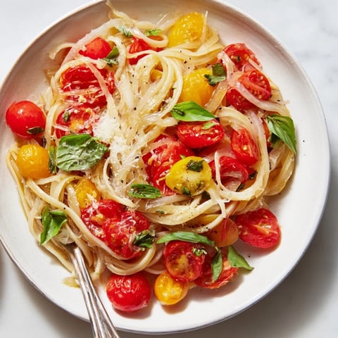 A steaming skillet of Cozy Fireplace One-Pan Tomato Basil Pasta with vibrant red tomatoes.