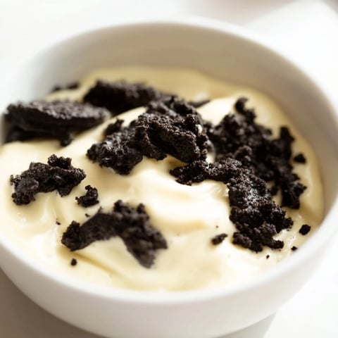 A layered glass showcases creamy vanilla pudding topped with crushed Oreos, a classic dessert.