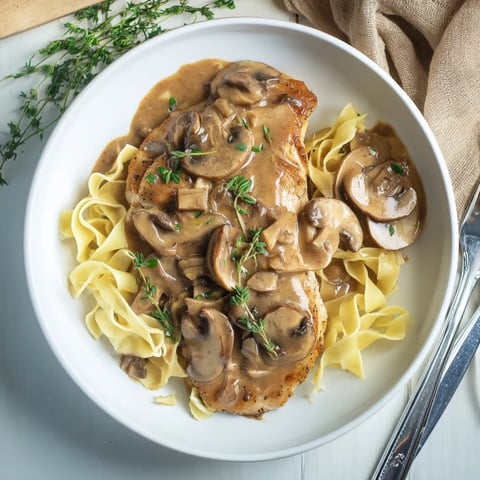 Golden-brown pan-seared chicken breasts simmered in a rich, creamy Marsala mushroom sauce, served over fettuccine pasta and garnished with fresh parsley.