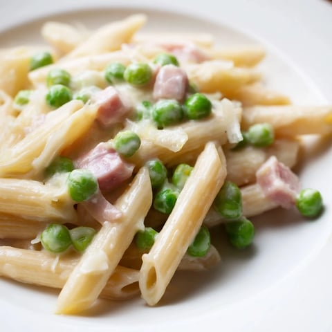 Steaming Spring Pea & Ham Pasta with penne, peas, and diced ham in a creamy Parmesan sauce, ready to serve.