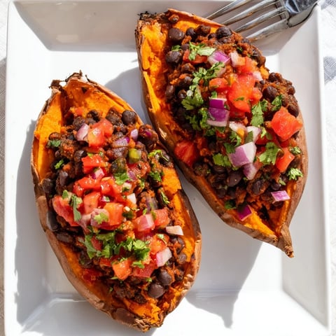 Roasted sweet potatoes with chipotle black beans and zesty tomato salsa garnished with avocado and cilantro.  