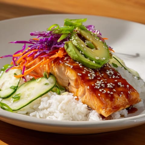 A close-up shot of a sweet chili salmon rice bowl with vibrant, fresh vegetable toppings.