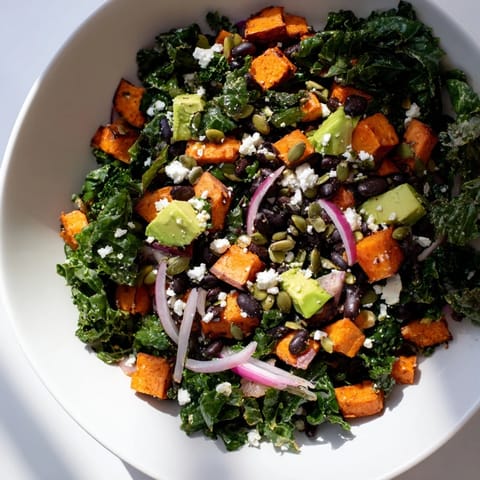 Freshly prepared massaged kale salad, combining roasted sweet potato and black beans for a hearty meal or side.