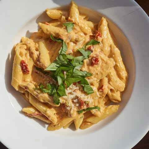 A bowl of Sun-Dried Tomato & Cottage Cheese Pasta Sauce, garnished with fresh basil, smells divine.