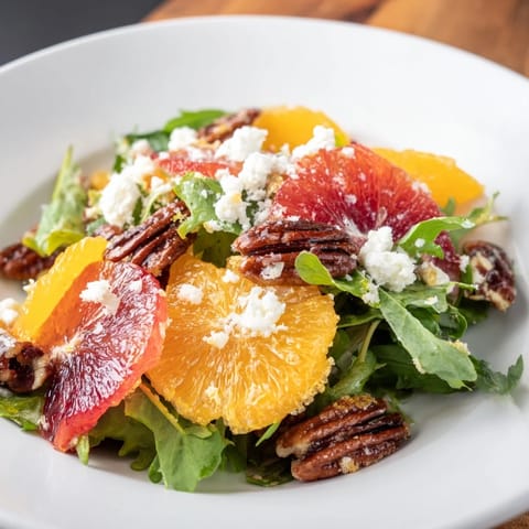 Close-up of Winter Citrus & Candied Pecan Salad: a colorful, refreshing mix with candied pecans and goat cheese.