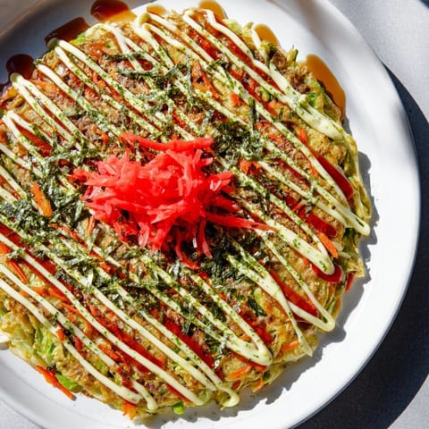 A close-up of fluffy Japanese Okonomiyaki, overflowing with cabbage and layered with beautiful toppings.