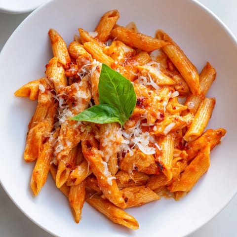 Hearty Tomato Basil Chicken Pasta tossed in a garlicky red sauce, served steaming hot with a sprinkle of grated Parmesan and fragrant basil.  