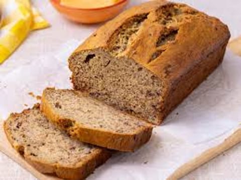 Freshly baked banana bread loaf sliced on a wooden board, golden and moist