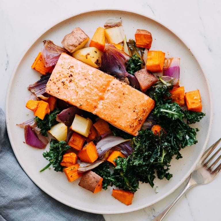 Flaky cooked sheet-pan salmon sits atop tender vegetables, awaiting a squeeze of fresh lemon juice.