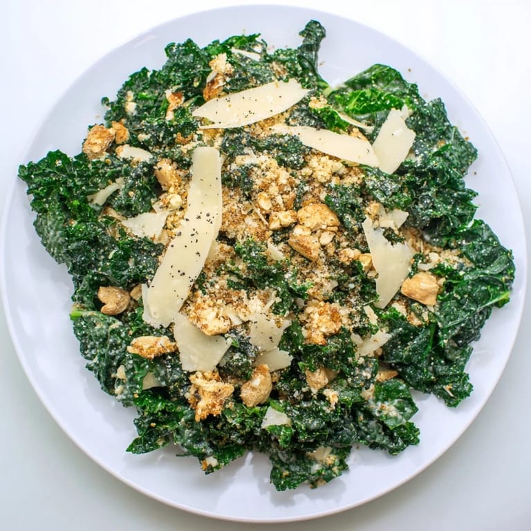 Garlic Parmesan Kale Salad served in a rustic bowl, garnished with fresh cracked pepper and a wedge of lemon on the side.
