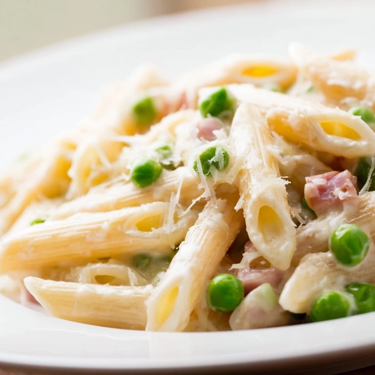 A close-up of Spring Pea & Ham Pasta in a skillet, garnished with parsley and Parmesan for a cozy meal.
