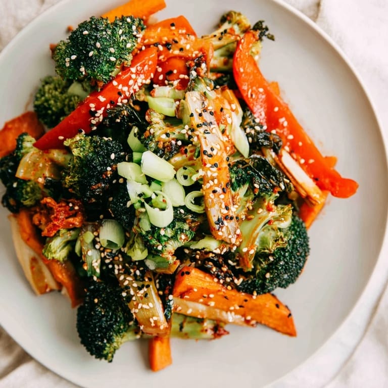 Steam rises from a vibrant bowl of Comforting Ferried Veggie Winter Stir-Fry, featuring tender winter vegetables and chopped kimchi garnished with green onions.