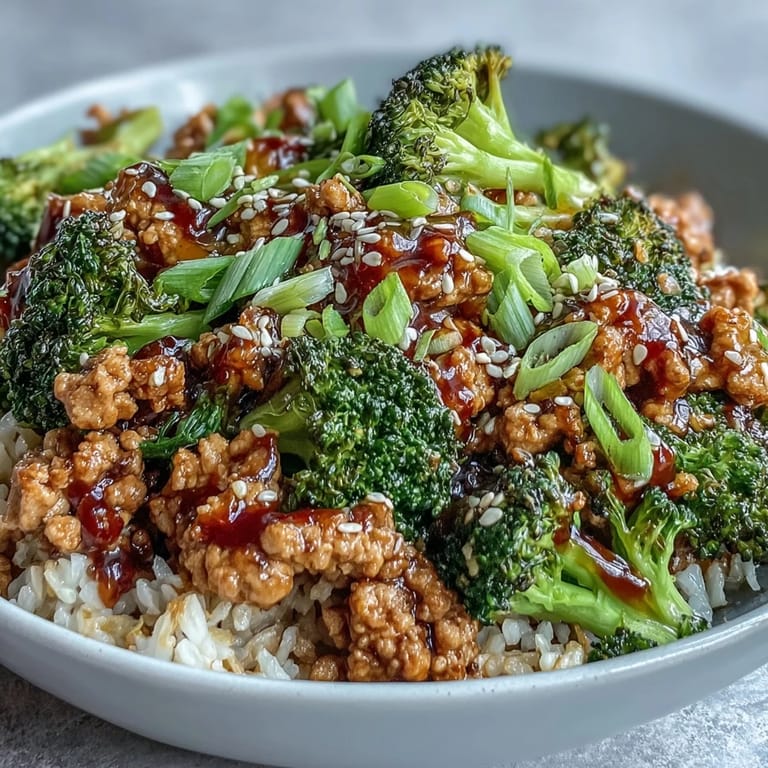 Garnished with green onions and sesame seeds, these easy Asian-inspired dinner bowls are steaming on a white ceramic plate.