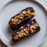 Chocolate Date Snickers: Imagine glistening dark chocolate coating delightful peanut butter stuffed dates, ready to enjoy.