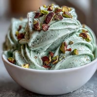 Creamy homemade pistachio gelato with roasted nuts and silky smooth texture in a bowl.  