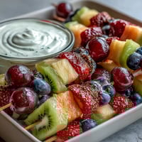 Rainbow Fruit Skewers with Honey Dip: colorful, juicy fruits threaded on skewers, served with a creamy honey-yogurt dip for a healthy snack.