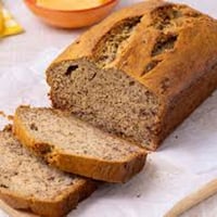 Freshly baked banana bread loaf sliced on a wooden board, golden and moist
