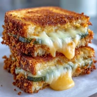 Golden fried pickle grilled cheese explosion with melted cheese and crispy bread.
