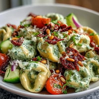 Vibrant Creamy Pesto Tortellini Picnic Salad with fresh cherry tomatoes and pine nuts.